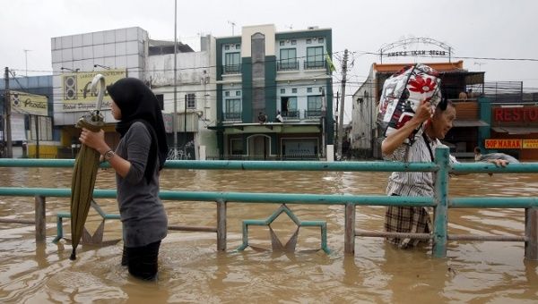 Indonesian residents hold to an iron railing as they wade through flood water in Jakarta, Indonesia.