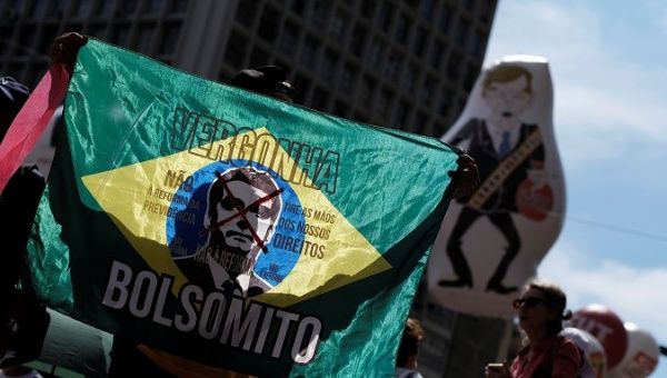 Protester holds a Brazilian flag with President Jair Bolsonaro image and the words: 