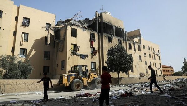Palestinians are seen near an apartment block that was hit by an Israeli air strike, in the northern Gaza Strip