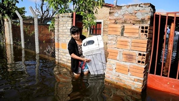 A woman carries her belongings in a flooded street, after heavy rains caused Paraguay River to overflow, in a neighbourhood on the outskirts of Asuncion, Paraguay. 