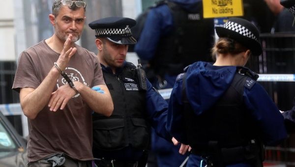 A Greenpeace activist waves while being detained by police after blocking the entrance to BP headquarters in London, Britain May 20, 2019. 