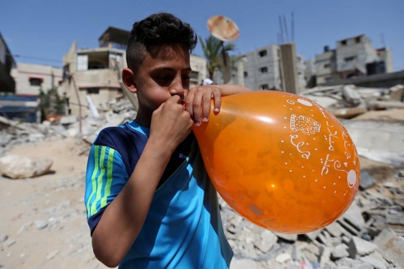 A Palestinian boy blows up a balloon to be hung over the ruins of a house that was destroyed in recent Israeli air strikes, in Rafah in Gaza.