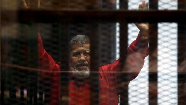 Egypt's deposed president Mohamed Mursi greets his lawyers and people from behind bars in this file photo. 