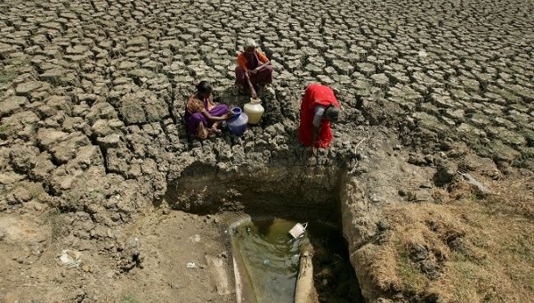 Women fetch water from an opening made by residents at a dried-up lake in Chennai, India.