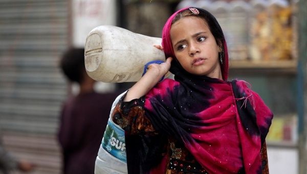 A girl from an Afghan refugee family carries bottles to be filled from a nearby tap in a low-income neighborhood in Lahore, Pakistan June 20, 2019.