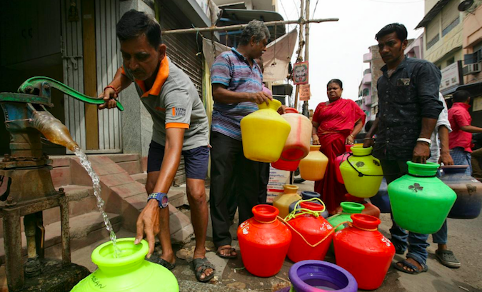 A man uses a hand-pump to fill up a container with drinking water as others wait in a queue on a street in Chennai, India, June 17, 2019.