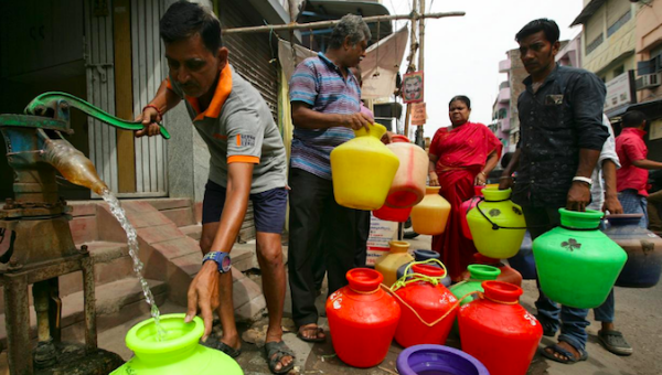 A man uses a hand-pump to fill up a container with drinking water as others wait in a queue on a street in Chennai, India, June 17, 2019.