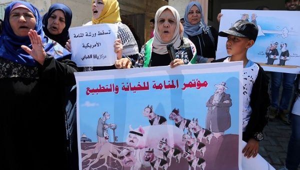 A Palestinian woman holds a banner showing a caricature of Arab leaders and reading: 