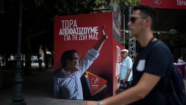 A man pasts a poster depicting PM Alexis Tsipras in Athens, Greece, July 6, 2019.