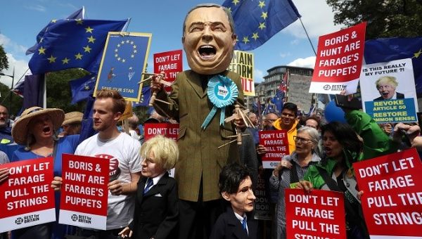 Person dressed as Brexit Party leader Nigel Farage holds puppets depicting Boris Johnson and Jeremy Hunt in London, Britain July 20,2019. 