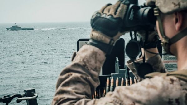 A U.S. Marine observes an Iranian fast attack craft from USS John P. Murtha during a Strait of Hormuz transit, Arabian Sea off Oman, in this picture released by U.S. Navy on July 18, 2019..