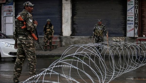 Indian security forces personnel stand guard next to concertina wire laid across a road during restrictions after the government scrapped special status for Kashmir. 