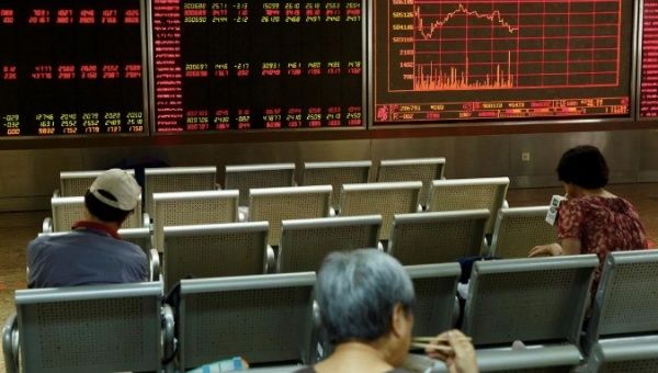 People sit in front of a board showing market information at a securities brokerage house in Beijing, China Aug. 5, 2019.