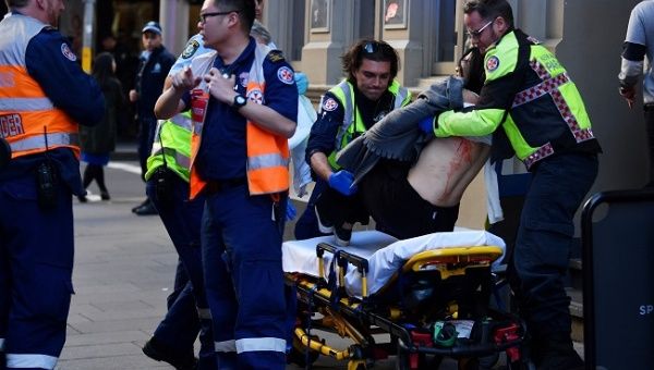 A woman is carried by paramedics, as police officers investigate a scene following reports of a stabbing in Sydney, Australia, August 13, 2019.