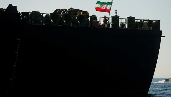 A crew member raises the Iranian flag on Iranian oil tanker Adrian Darya 1, previously named Grace 1, as it sits anchored after the Supreme Court of the British territory lifted its detention order, in the Strait of Gibraltar, Spain. 
