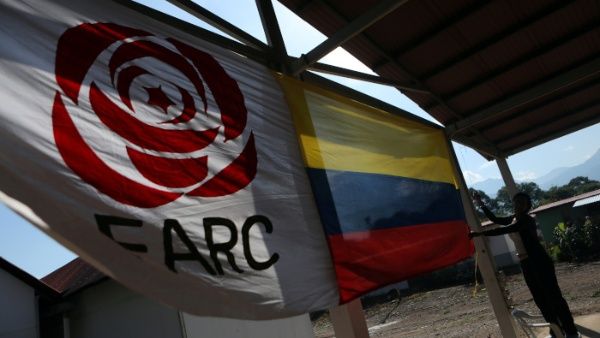 A woman hangs a Colombian flag next to the flag of the political party of the Revolutionary Common Alternative Force (FARC)