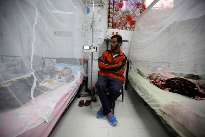 A man sits next to his son as he receives attention for dengue fever at Hospital Escuela in Tegucigalpa, Honduras, July 29, 2019.