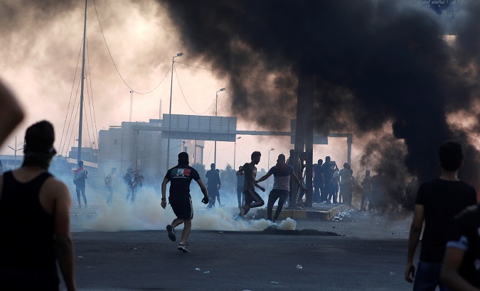 Demonstrators disperse as Iraqi security forces use tear gas during a protest after the lifting of the curfew, following four days of nationwide anti-government protests,
