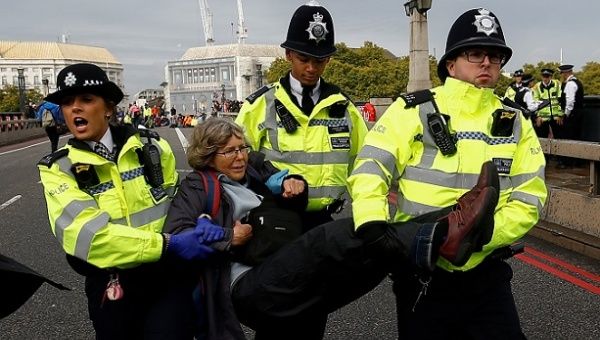 Police officers detain an activist at Lambeth Bridge during the Extinction Rebellion protest in London, Britain October 7, 2019. 