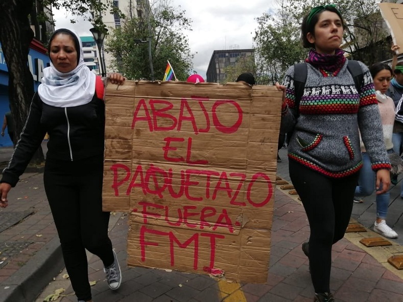 Women hold sign reading 'Down with the economic policy package, Get out IMF', Quito, Ecuador, October 12, 2019.