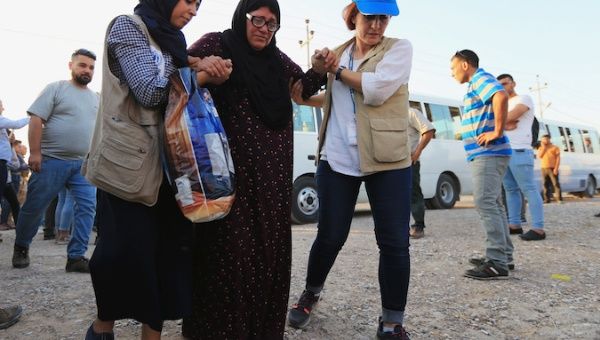 U.N. workers help a Syrian displaced woman, who fled violence after the Turkish offensive against Syria, upon arrival at a refugee camp in Bardarash on the outskirts of Dohuk, Iraq October 16, 2019. 