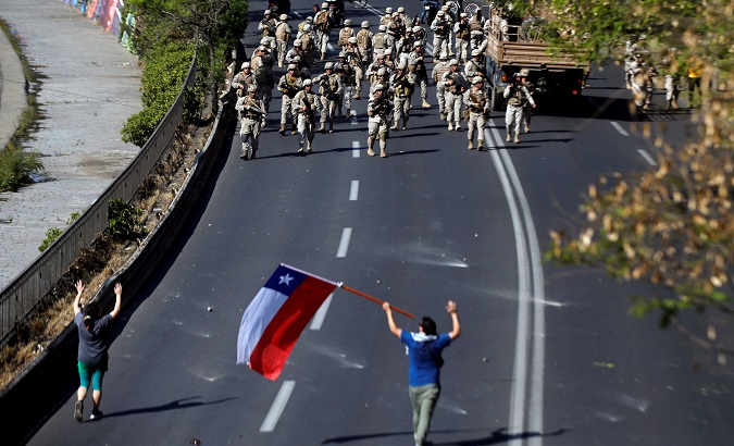 Chilean soldiers stand guard with their weapons during a protest against Chile's state economic model in Santiago Oct. 20, 2019.