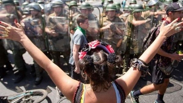A young woman stands in front of a group of anti-riots police in Chile, Oct. 24, 2019.