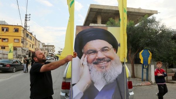 A man adjusts Hezbollah flag on a vehicle decorated with a poster of Lebanon's Hezbollah leader Sayyed Hassan Nasrallah in the southern village of Kfar Kila, Lebanon, October 25, 2019. 