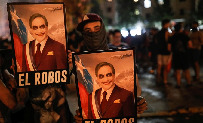 Demonstrators hold posters depicting Chilean President Sebastian Pinera during a protest against Chile's state economic model in Santiago, Chile October 25, 2019.