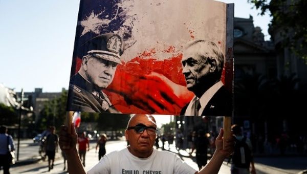 Demonstrator Holding a placard with an image depicting Chile's President Sebastian Pinera and the late dictator Augusto Pinochet.