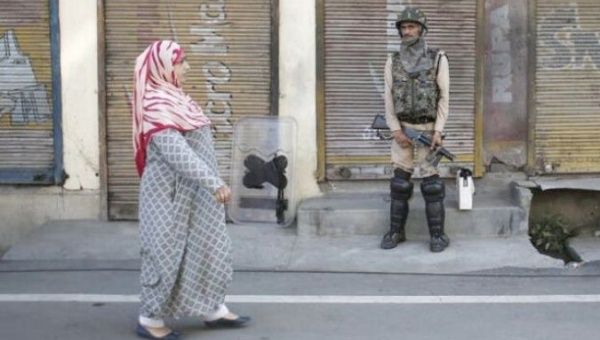 A Kashmiri woman walks past an Indian soldier.