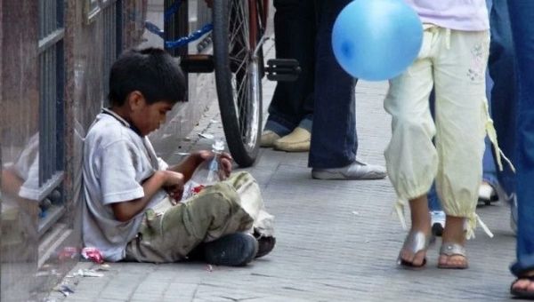 Child affected by social inequality remains seated on the sidewalk, Argentina, 2019.