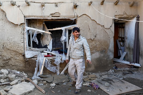 A man inspects a damaged house at the site of an attack in a U.S. military air base in Bagram.