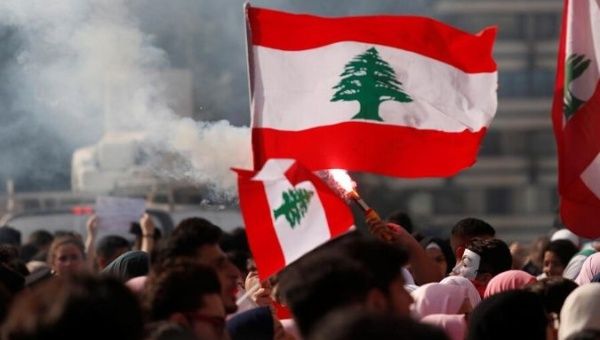 University students light a torch and wave Lebanese flags during anti-government protest in Beirut, Lebanon, Nov. 6, 2019. 