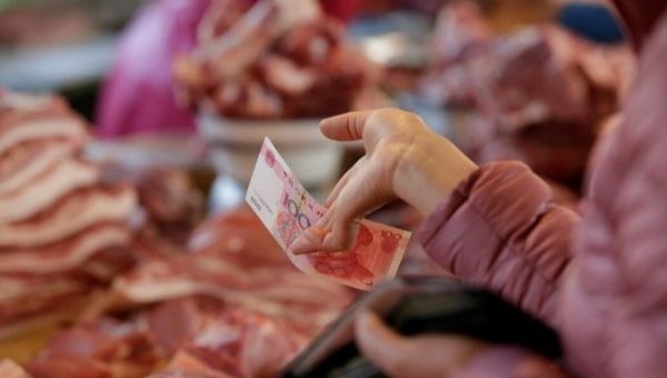 A customer buys pork from a vendor at a market in Beijing, China. 