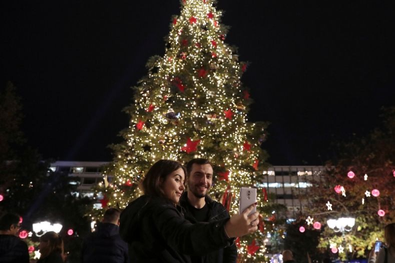 A couple takes a selfie in front of a Christmas tree on Syntagma square in Athens, Greece.