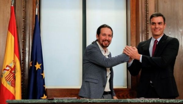 Spain's acting Prime Minister Pedro Sanchez and Unidas Podemos leader Pablo Iglesias shake hands as they present their coalition agreement at Spain's Parliament in Madrid, Spain, Dec.30, 2019.