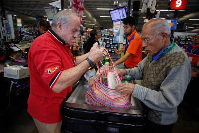 An employee helps a man to arrange groceries in a bag at a supermarket which no longer provides plastic bags for customers to carry products, in Mexico City, Mexico January 2, 2020.