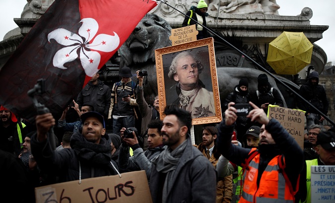 Citizens hold a placard with a portrait of Macron as King Louis XVI at a demonstration in France, January 9, 2020.