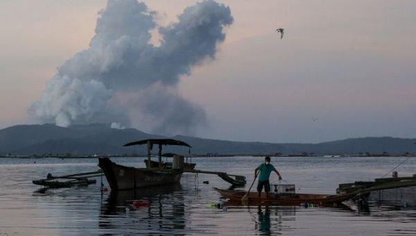 A fisherman catches fish as the Taal Volcano continuously errupts in Talisay, Batangas, Philippines, Jan. 16, 2020.