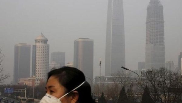 A woman wearing a protective mask makes her way in a business district on a heavily polluted day in Beijing, China January 3, 2016.