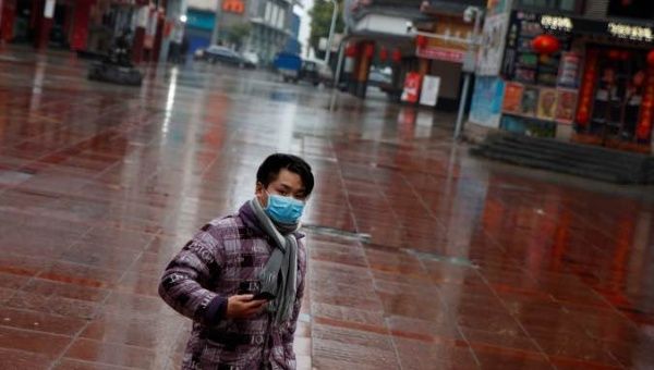 A man wearing a face mask walks in a deserted shopping area in Jiujiang