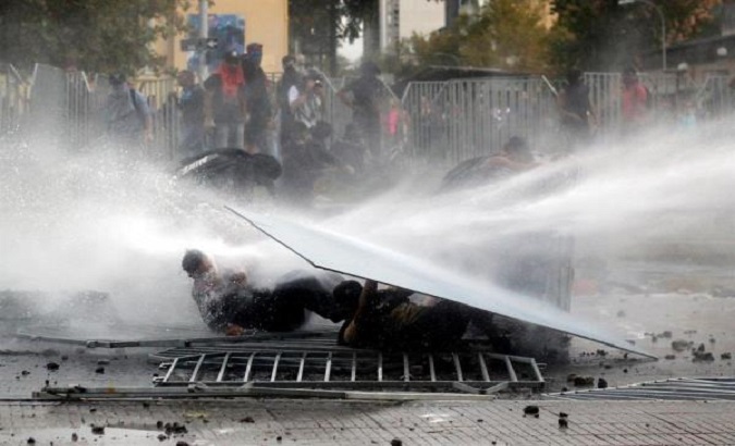 Military Police throwing water at protesters in Santiago, Chile, March 11, 2020.