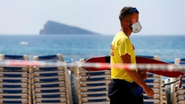 A lifeguard walks with a mask on the eastern beach of Benidorm, in Alicante, Spain, closed to the public. March 14, 2020. 