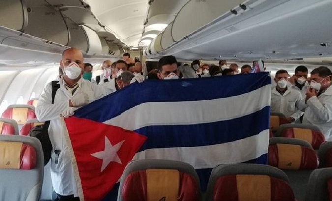 Cuban health workers hold a flag of their country inside an airplane bound for Italy, March, 2020.