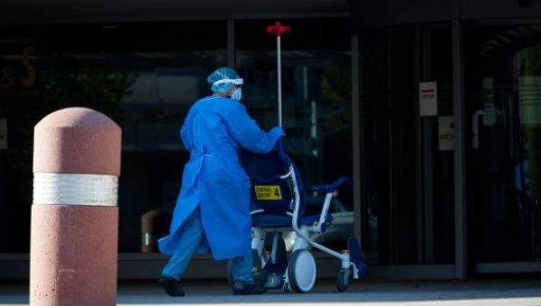 A healthcare worker wearing personal protective equipment (PPE) pushes a wheelchair into Kings County Hospital in New York, the United States, on April 28, 2020.