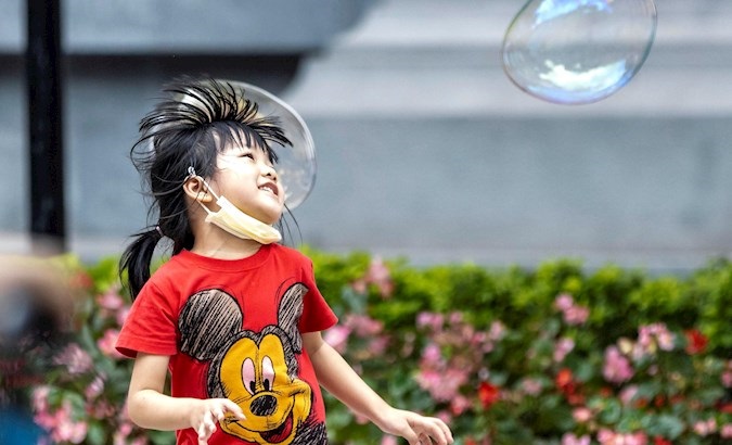A girl wearing a mask plays with soap balloons in Guangzhou, China, May 1, 2020.