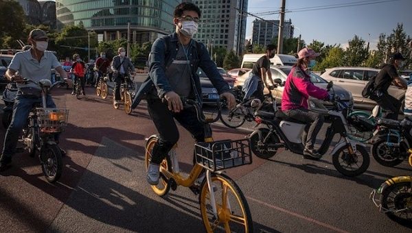 People ride bicycles and scooters during evening rush hour, Beijing, China, May 19, 2020.