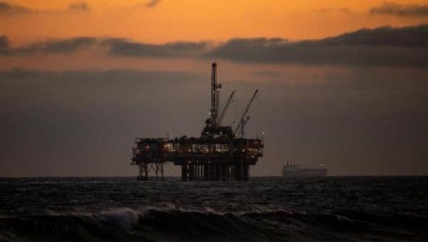 An oil rig sits off the shore at sunset in Huntington Beach, California, U.S., May 15, 2020.