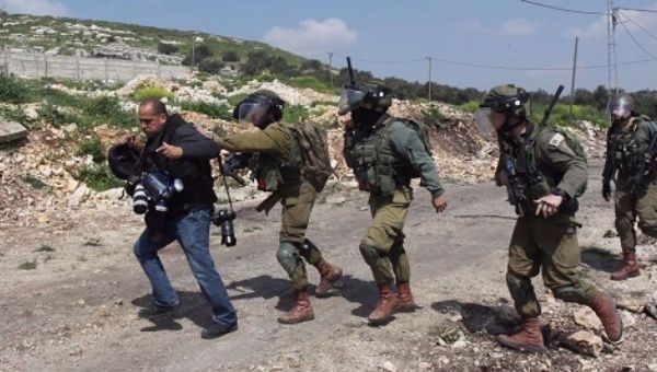 Israeli forces scuffle with a Palestinian photojournalist during a protest against construction of Israeli settlements in the occupied West Bank.